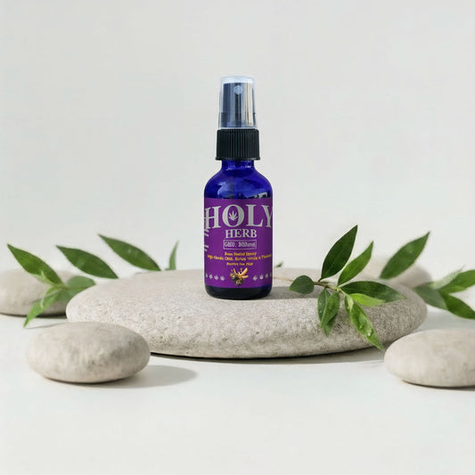 Purple bottle labeled 'Holy Herb' on a white surface with stones and green leaves.